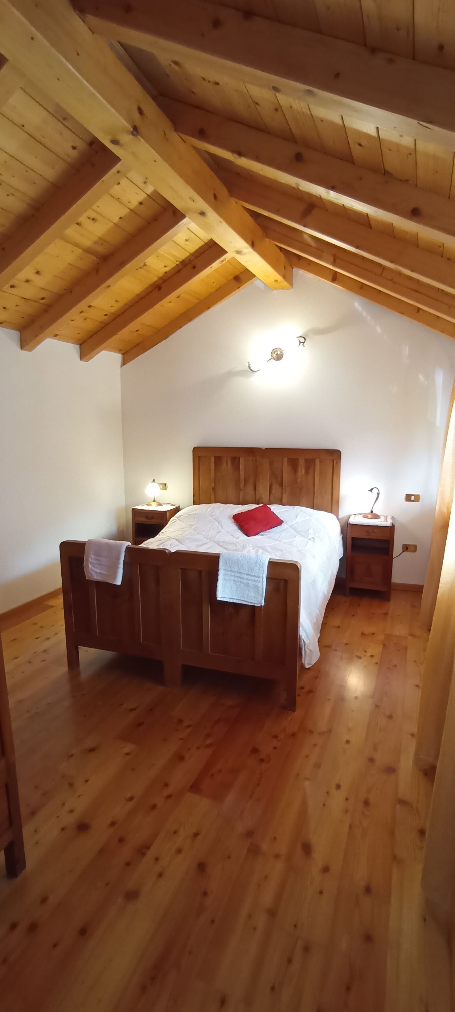 La camera con letto alla francese, sotto le travi in legno